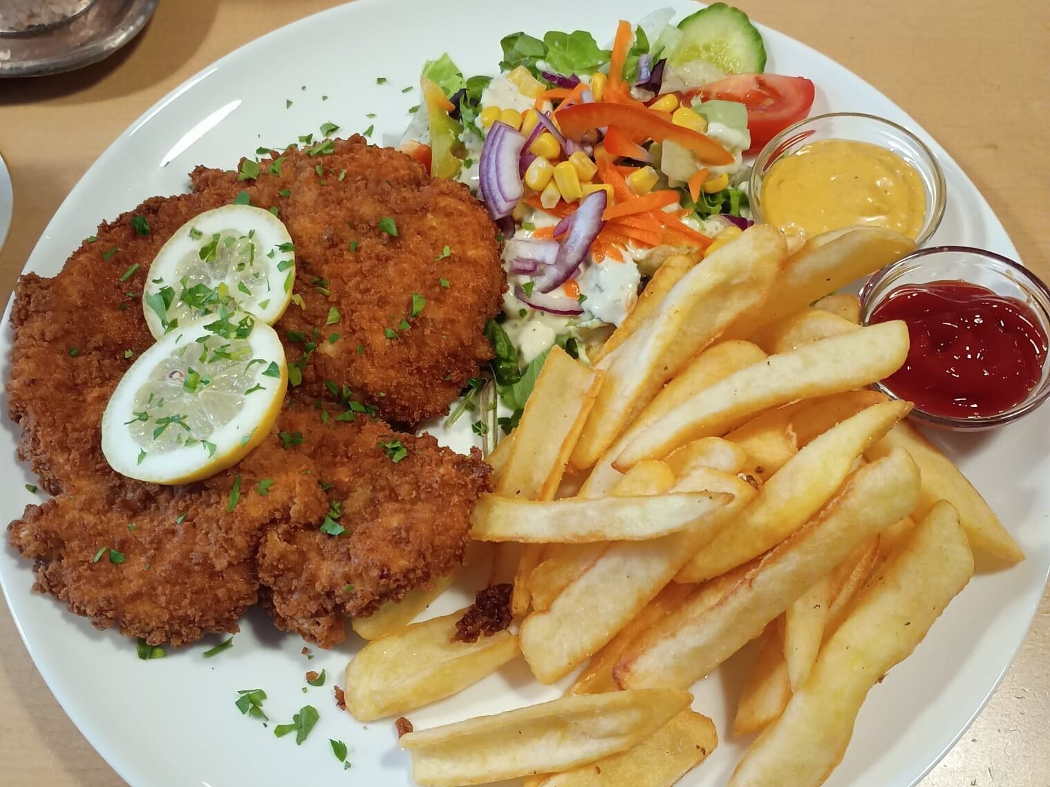 Schitzel paniert mit Salat und dazu Pommes als Beilage